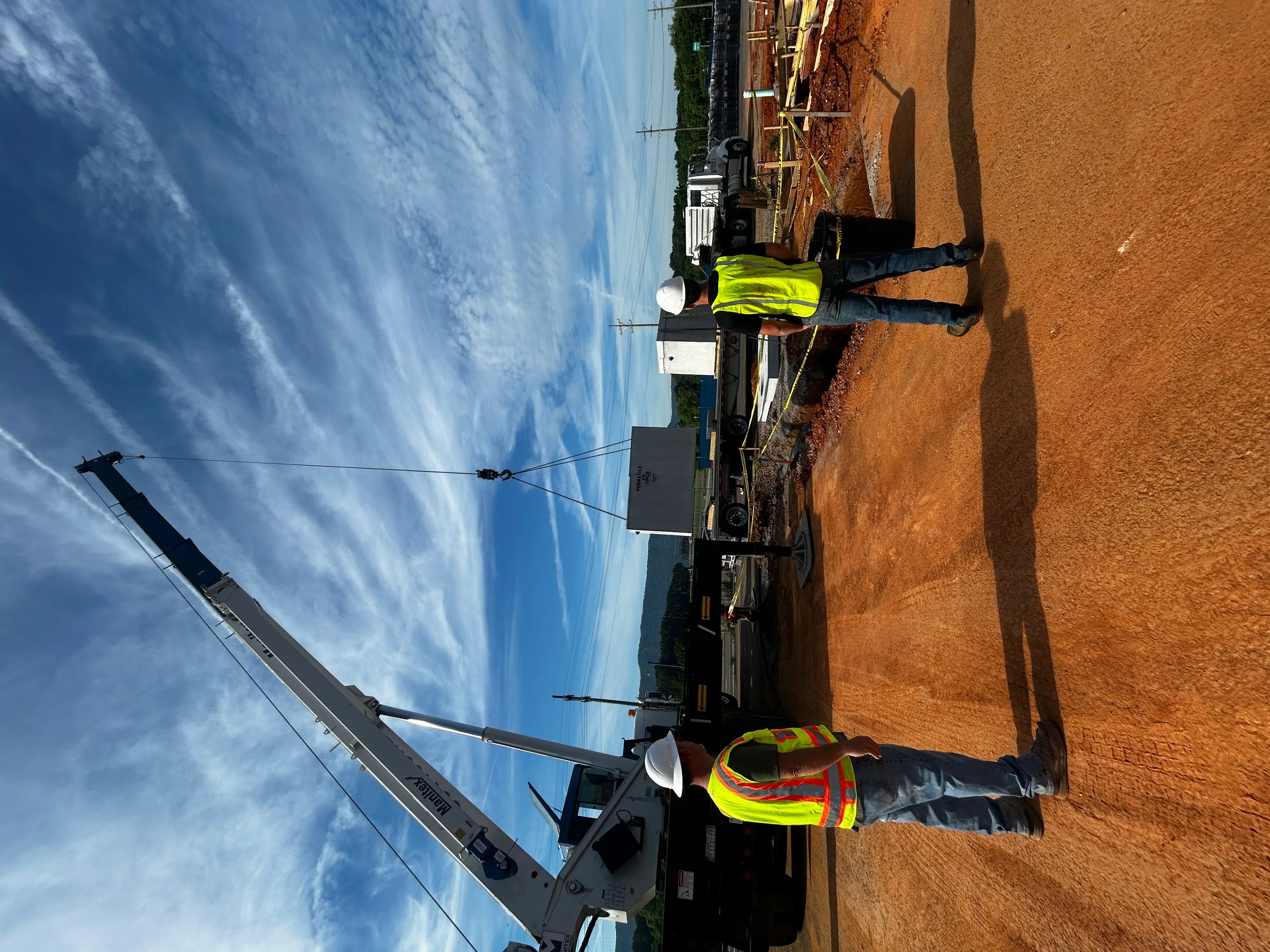 Septic tank installation with excavation equipment and workers in safety gear on clay soil site