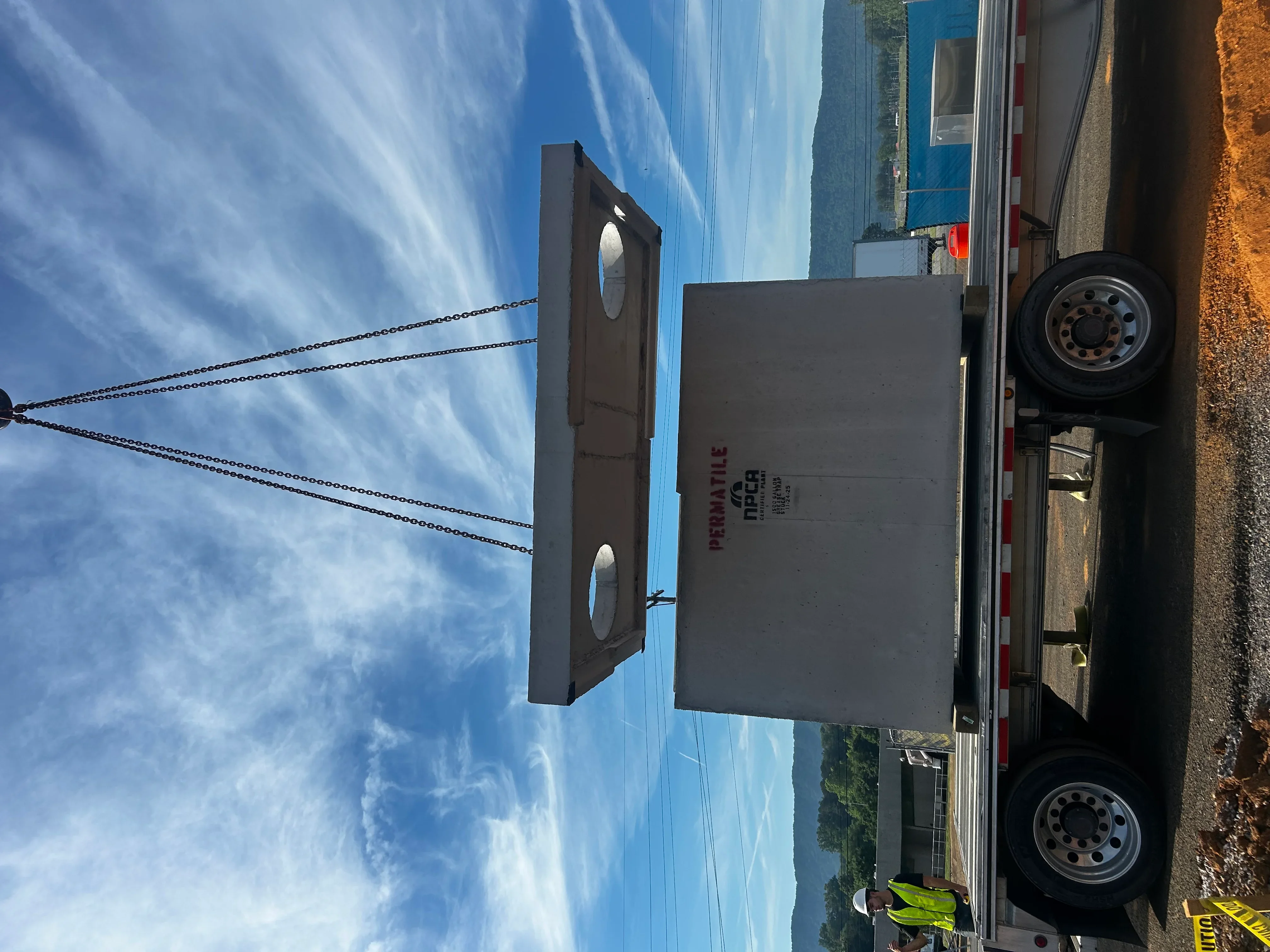 Concrete septic tank with dual access ports being positioned with chain rigging during installation