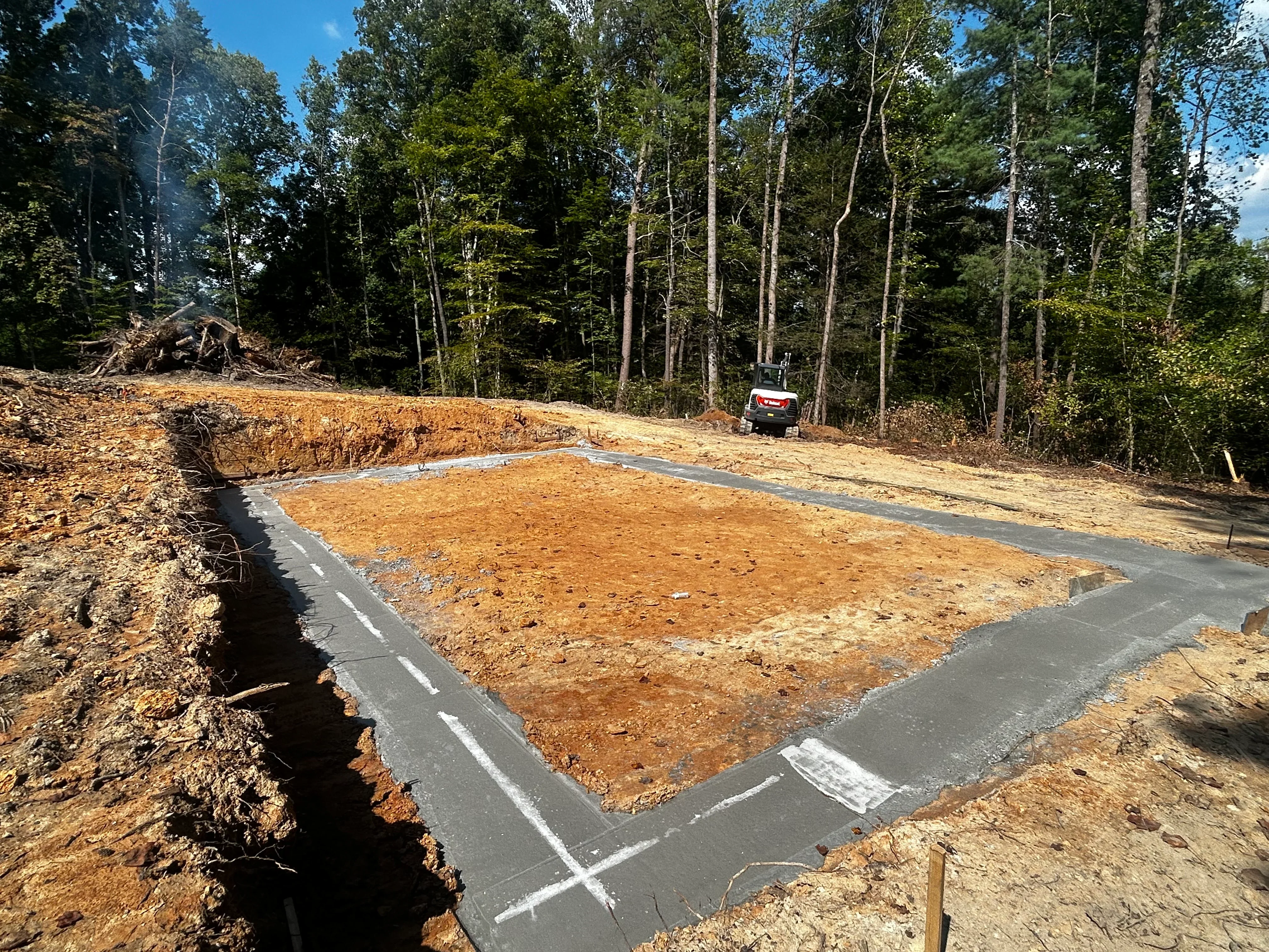 Septic tank foundation with geotextile fabric lining, excavated site with proper grading in wooded area