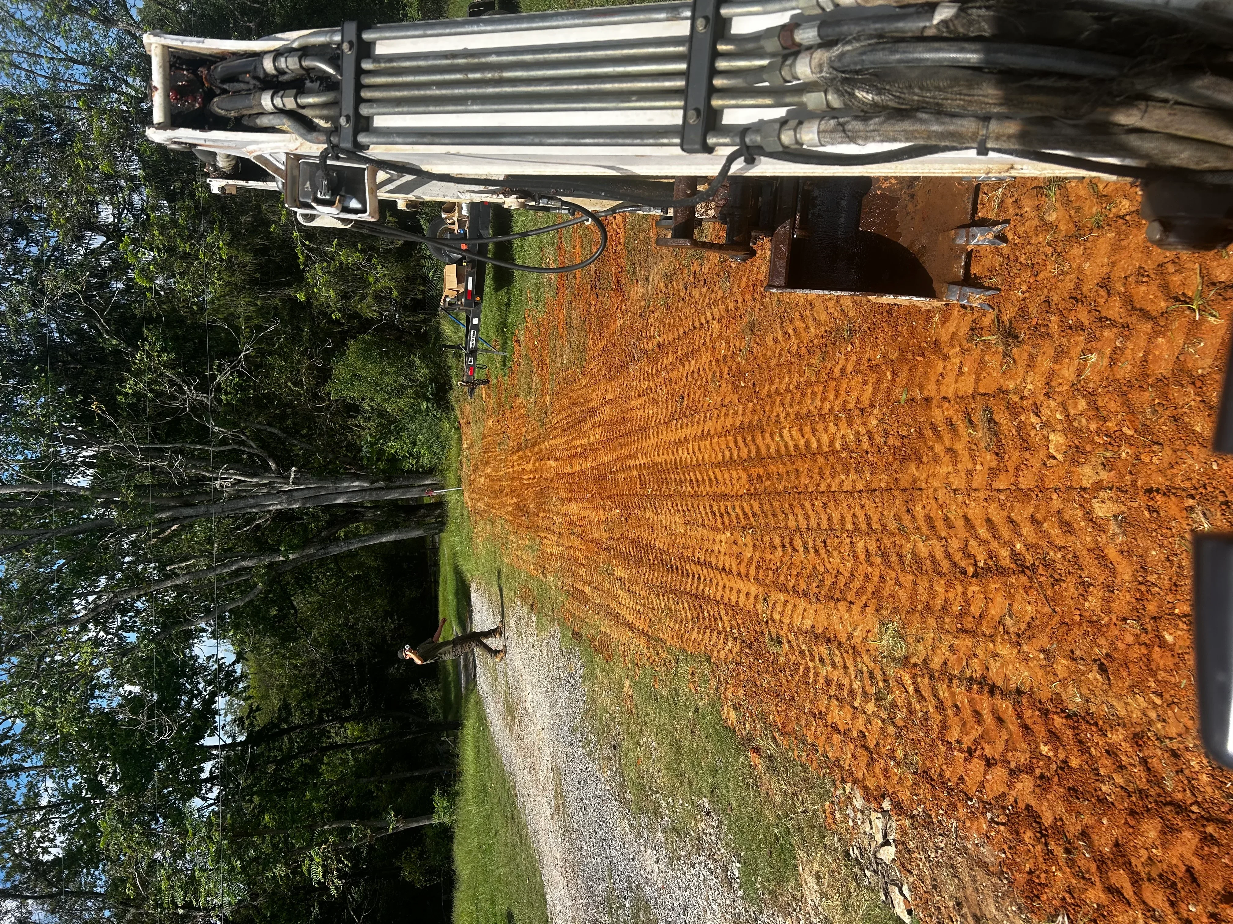 Septic tank installation with corrugated metal tank, inlet/outlet pipes, and excavated soil foundation