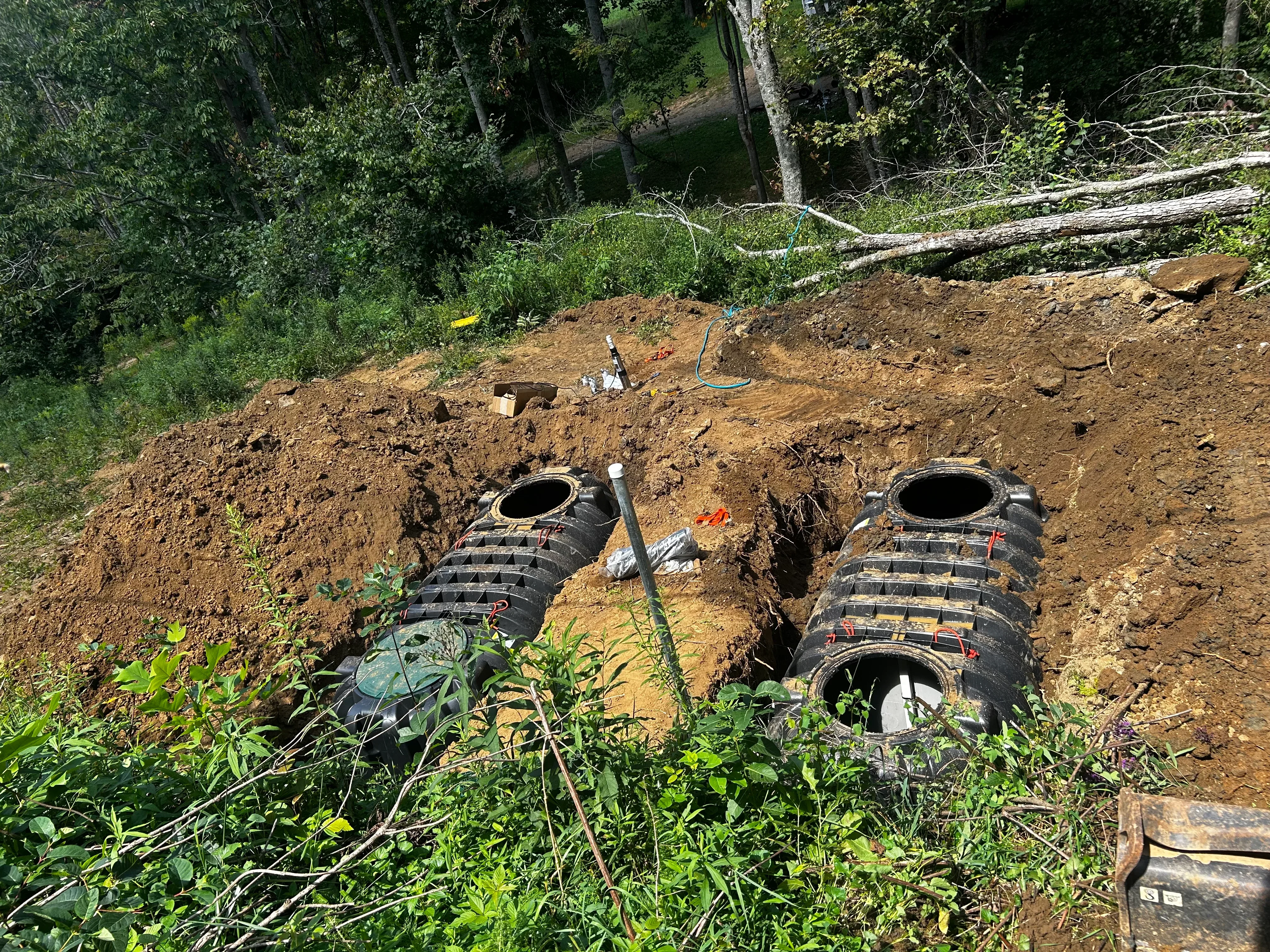 Two black septic tanks installed in excavated soil with proper spacing and connections