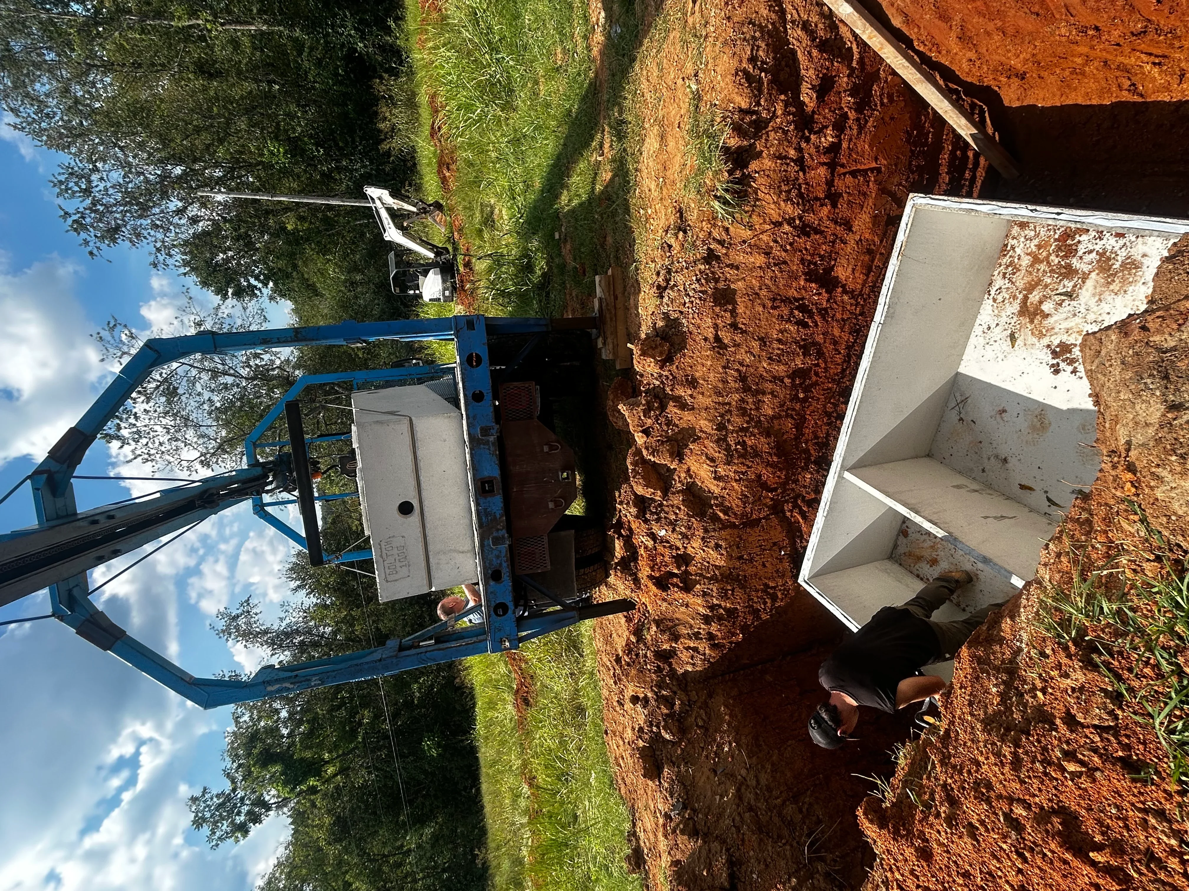 Concrete septic tank with access ports installed in excavated red clay soil
