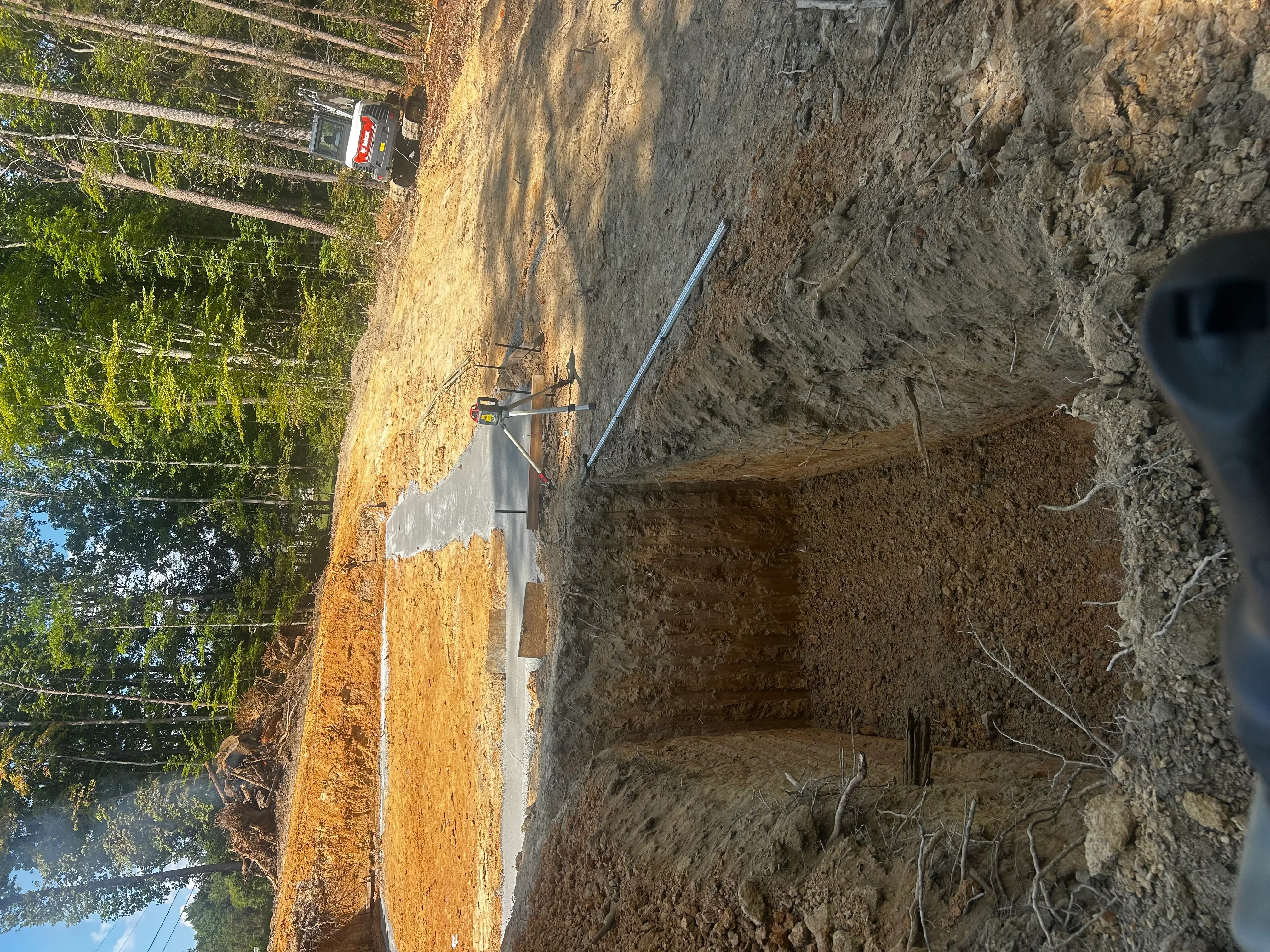 Concrete septic tank installed in excavated pit with soil grading and PVC piping connections