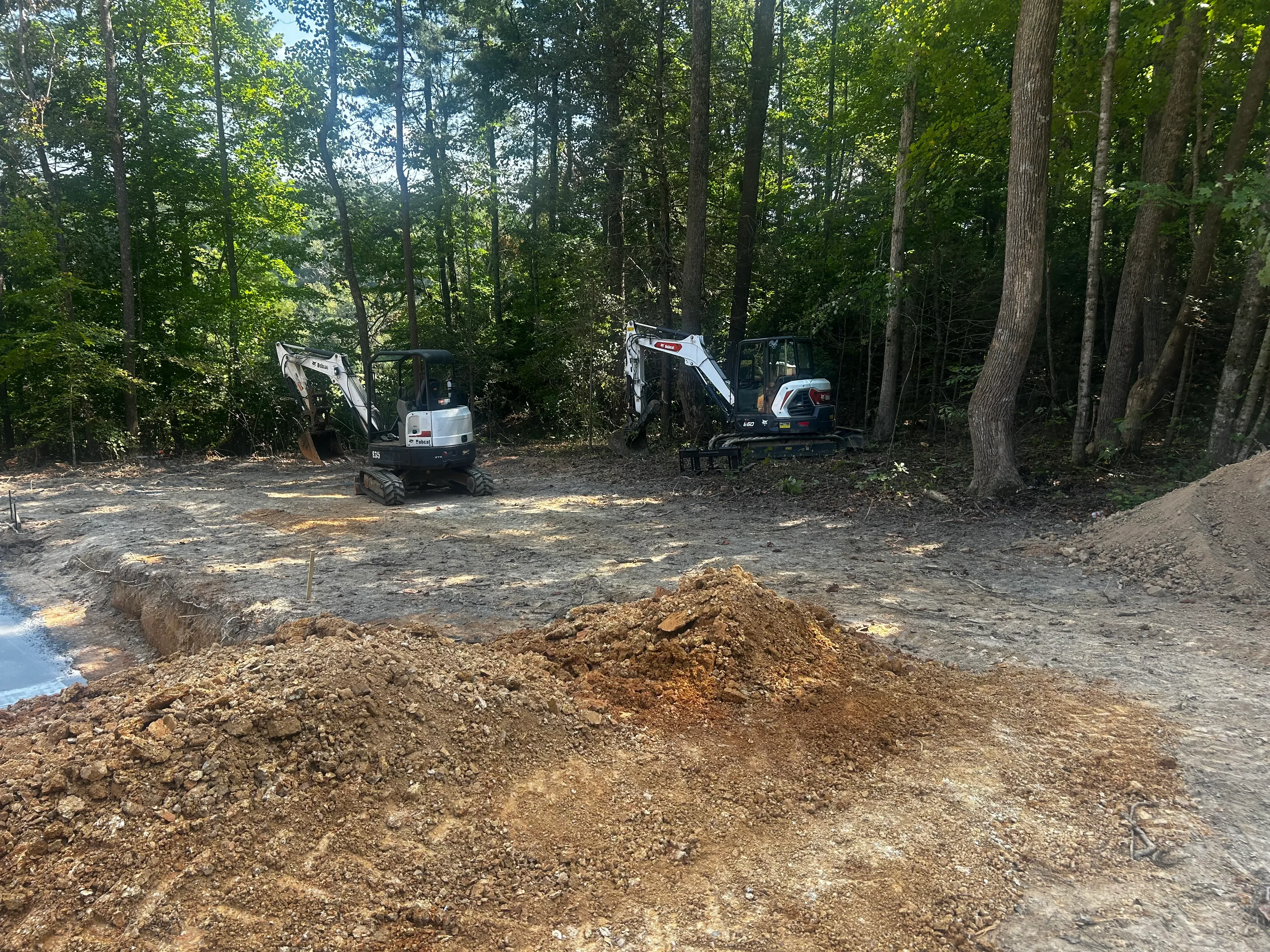 Compact excavators and earth excavation for septic system installation in wooded area