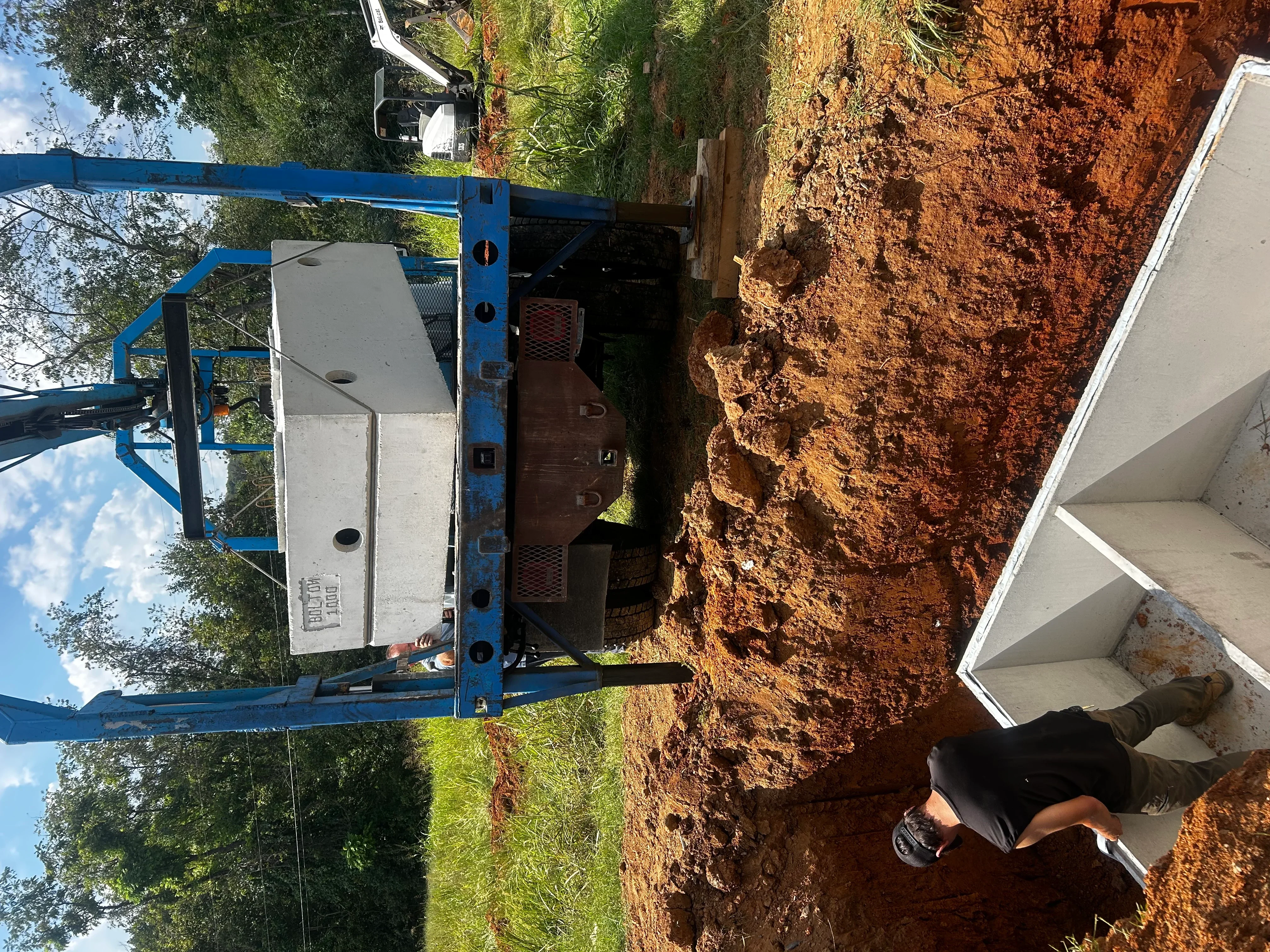Septic tank installation with blue lift equipment on excavated clay soil site